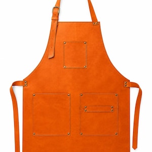 May include: A bright orange apron featuring an adjustable neck strap with a metal buckle, one chest pocket, and two lower pockets. The pockets are secured with metallic rivets at each corner, and the apron includes side ties for fastening.