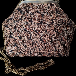 Puede incluir: Un bolso estructurado con cierre de broche de presión en acabado de latón antiguo. El exterior está cubierto con piezas de tela superpuestas en forma de roseta con un patrón de estampado animal en marrón, negro y beige. Incluye una correa de cadena de latón.
