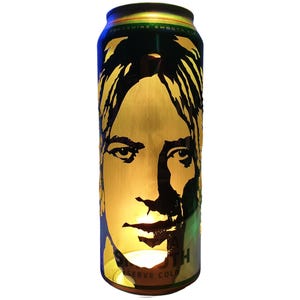 Könnte beinhalten: Eine hohe, zylindrische Dose mit einem goldfarbenen Gesichtsdesign. Die Dose hat einen schwarzen und grünen oberen und unteren Teil, mit den Worten "Yorkshire Smooth" und "Serve Cold". Das Gesicht ist ein stilisiertes Porträt.