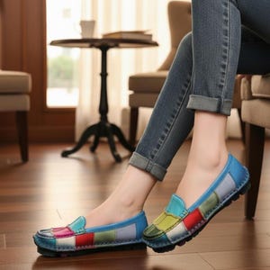Puede incluir: Mocasines de cuero con patchwork multicolor en tonos azules, verdes, rojos y rosas. Los zapatos tienen una puntera redondeada y un tacón bajo. La imagen muestra los zapatos con vaqueros azules.