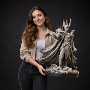 Puede incluir: Una estatua gris detallada de un personaje de El Señor de los Anillos, con un casco con púas, armadura y una capa fluida. La estatua es sostenida por una persona con una chaqueta beige y vaqueros oscuros sobre un fondo negro.