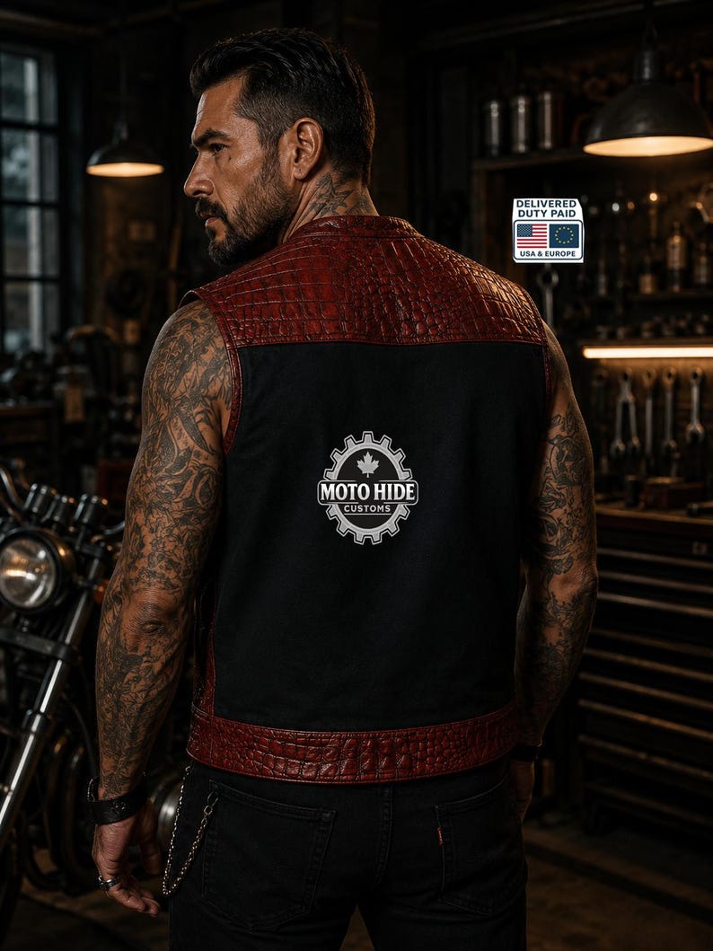 May include: A black and red leather vest with a textured, crocodile-like pattern on the shoulders and trim. The vest features the "MOTO HIDE CUSTOMS" logo on the back. The vest is worn over a black shirt and black jeans.