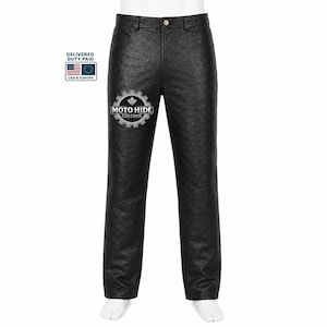 May include: Black trousers featuring a textured ostrich-like pattern, a button closure at the waist, and belt loops. The right leg displays a white circular logo with a gear design and the text MOTO HIDE CUSTOMS with a small maple leaf icon.