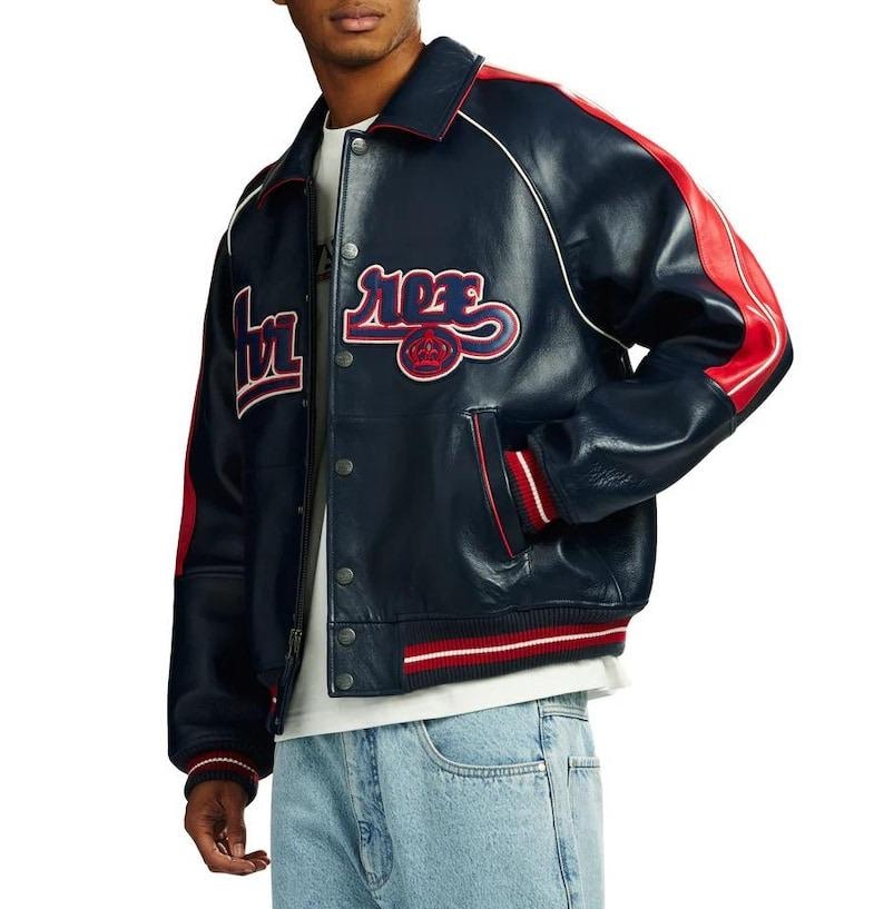 May include: Navy blue leather jacket with red and white accents. Features a button-up front, side pockets, and a white collar. The jacket has red stripes on the sleeves and the word "ROSE" in a script font on the chest.