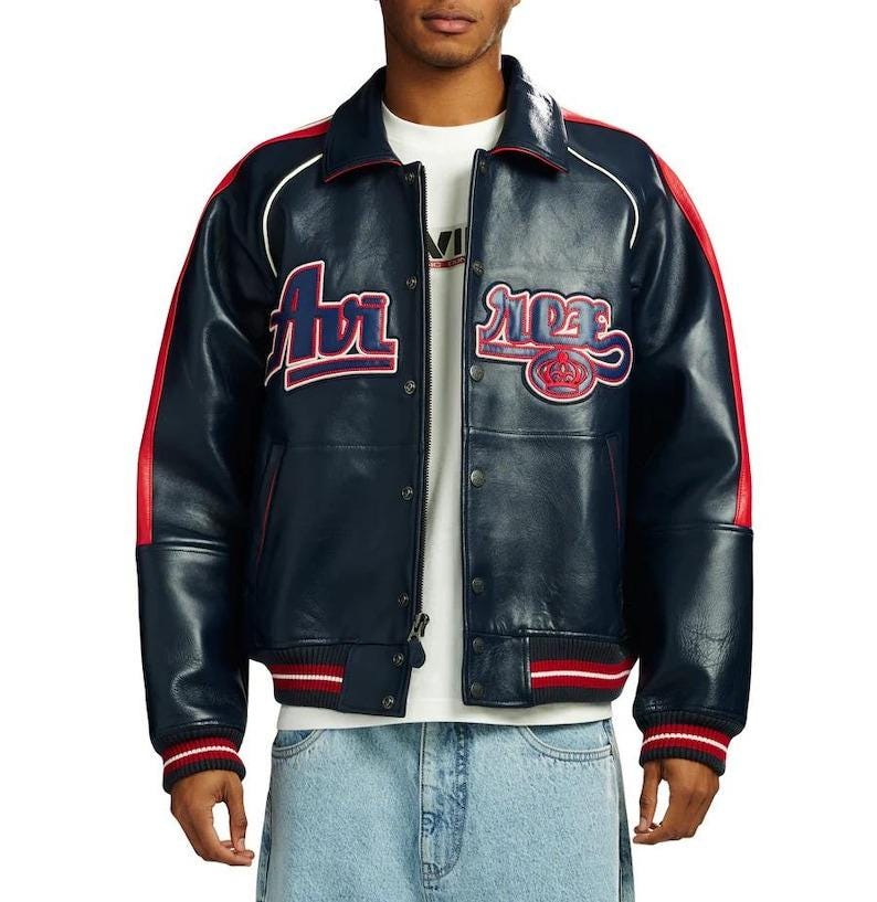 May include: Navy blue leather jacket with red and white accents. The jacket features the word "Air" in red and white lettering on the chest, and the word "Ride" with a crown logo. The jacket has a ribbed collar, cuffs, and hem.