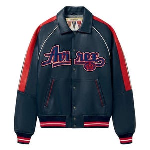 May include: Navy blue leather jacket with red stripes on the sleeves and white trim. The jacket features the text "Air Rex" in a script font across the chest. The cuffs and waistband have red and white striped detailing.
