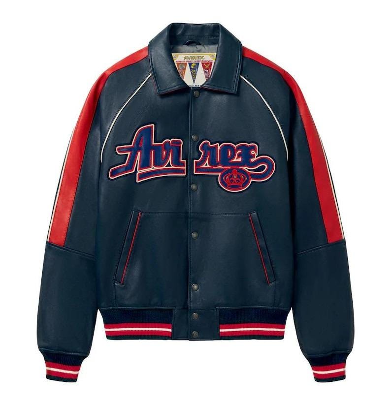 May include: Navy blue leather jacket with red stripes on the sleeves and white trim. The jacket features the text "Air Rex" in a script font across the chest. The cuffs and waistband have red and white striped detailing.
