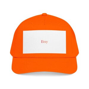 May include: Bright orange baseball cap with a white rectangular patch. The word "Etsy" is printed in red on the patch. The cap has a curved brim and a rounded crown.