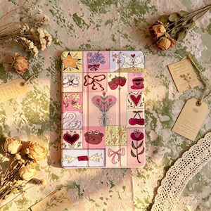 May include: A rectangular tablet case featuring a grid of colorful illustrations including a star, a bouquet, two rabbits, a butterfly, ribbons, strawberries, a coffee cup, flowers, a swan, a heart-shaped flower arrangement, cherries, a bear face, and a bow.