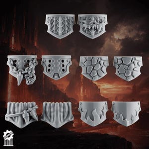 May include: A collection of eight gray, shield-shaped miniature armor pieces. Each piece features unique textured designs, including scales, a skull, chains, rivets, stone patterns, and flame motifs. The pieces are arranged against a dark, blurred background.