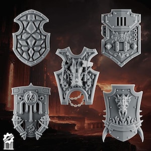 May include: Five gray miniature shields with intricate designs. The shields vary in shape and feature details like geometric patterns, dragon motifs, and weapon emblems. The shields are likely for tabletop gaming or model building.