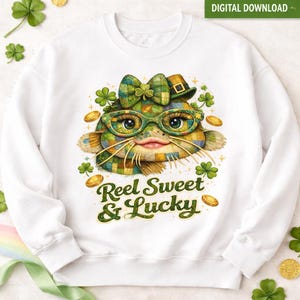 Op de afbeelding: Witte sweatshirt met een grillig meervalontwerp met een geruite strik, hoed en bril. Het ontwerp bevat klavers, gouden munten en de tekst "Reel Sweet & Lucky" in het groen. Digitale download beschikbaar.