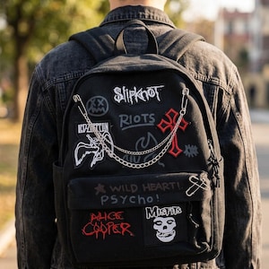 Puede incluir: Mochila negra con parches de bandas como Slipknot, Led Zeppelin y Misfits. La mochila tiene un bolsillo frontal, una cadena plateada y un imperdible. Los parches son rojos, blancos y negros.