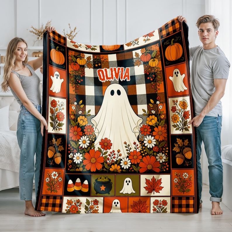 May include: A rectangular throw blanket featuring a central white ghost graphic above the name OLIVIA, surrounded by a patchwork pattern of orange and black buffalo plaid, pumpkins, autumn flowers, acorns, candy corn, and maple leaves.