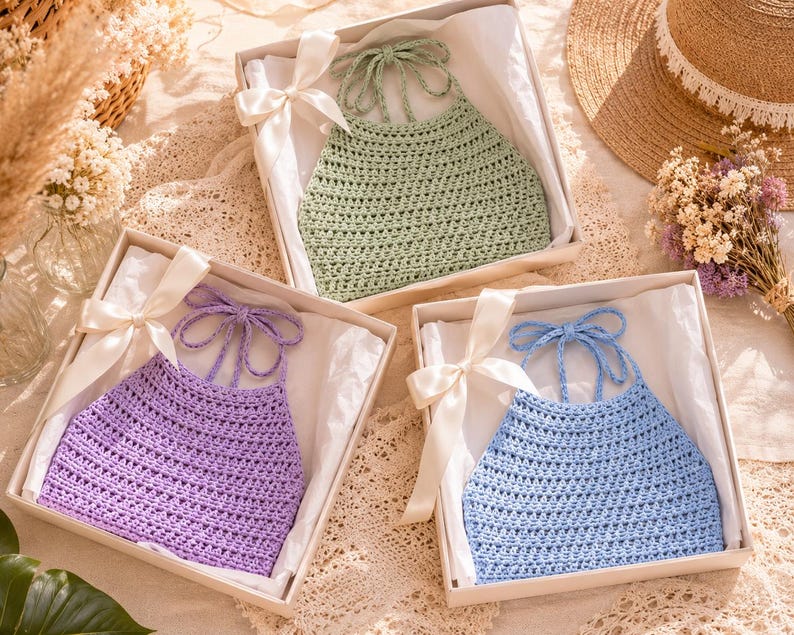 Puede incluir: Tres tops halter de ganchillo hechos a mano en cajas de regalo. Los tops son de colores pastel: lavanda, verde claro y azul claro. Cada top se presenta en una caja blanca con una cinta blanca atada con un lazo.