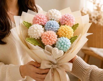 May include: A bouquet of crocheted flowers in pastel shades of pink, blue, yellow, and white, featuring textured spherical blooms and green crocheted leaves. The arrangement is wrapped in beige paper with a matching ribbon and a small crocheted heart.
