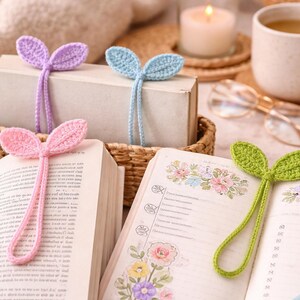 May include: A cozy scene featuring handmade crochet leaf bookmarks in pink, purple, blue, and green. The bookmarks are placed in open books with floral illustrations. A candle, coffee cup, and glasses are also in the frame.