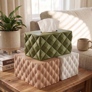 May include: A rectangular tissue box cover with a three-dimensional diamond-patterned surface. The top cover is olive green, while the two base covers are light beige and white. Each cover features a geometric, faceted texture across all visible sides.
