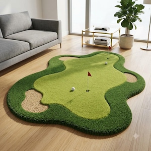 Puede incluir: Una alfombra de pelo cortado con forma de green de golf, con secciones de calle en verde claro, bordes de rough en verde oscuro y trampas de arena en color canela. Incluye dos hoyos con banderas rojas y dos pelotas de golf blancas.
