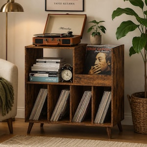 May include: A wooden record player stand with multiple compartments. The top shelf holds a vintage record player and a stack of books. The lower shelves are filled with vinyl records. A small alarm clock sits on the shelf. The stand is brown with a distressed finish.