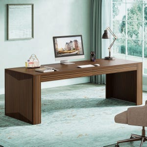 May include: A modern, dark brown wooden desk with a computer monitor, lamp, and office supplies. The desk has a minimalist design with vertical and horizontal lines. The desk is in a well-lit room with a window and a framed document on the wall.