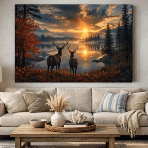 May include: A rectangular wall art print depicting two deer standing on a shore overlooking a lake at sunset. The scene features orange and yellow clouds, dark evergreen trees, and autumn foliage. The reflection of the sun is visible on the water.