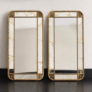 May include: Two rectangular wall mirrors featuring gold-toned twisted metal frames with rounded corners and decorative heart-shaped accents. The mirror glass is bordered by a white and gold marbled pattern, creating a distinct frame within the frame.