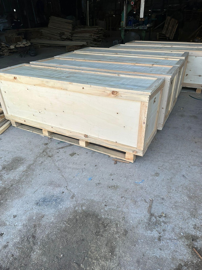 K&ouml;nnte beinhalten: Eine Reihe rechteckiger h&ouml;lzerner Transportkisten aus hellem Sperrholz und massivem Holzrahmen. Jede Kiste ist auf einer Holzpalette montiert und verf&uuml;gt &uuml;ber eine flache Oberseite sowie vertikale Seitenw&auml;nde mit sichtbarer Maserung.