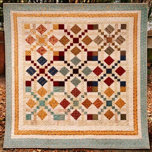 May include: A handcrafted quilt with a cream-colored background and a geometric pattern of diamonds and squares in shades of red, blue, gold, and brown. The quilt is bordered with a light blue floral print and a gold trim.