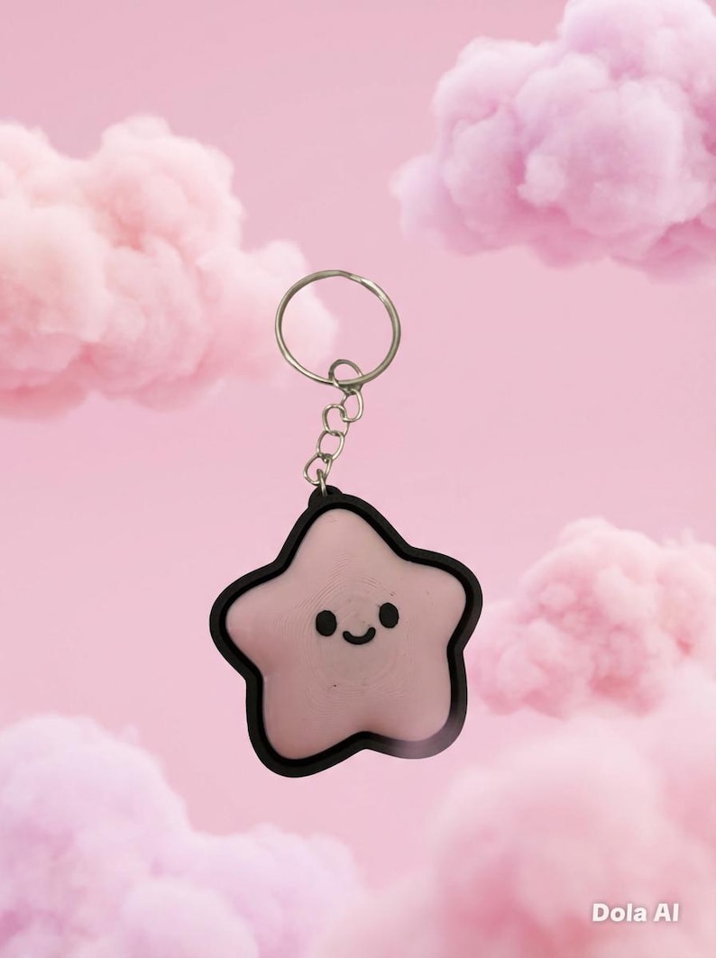 May include: A pink star-shaped keychain with a black outline and a smiling face. The keychain is attached to a silver ring and chain. The background features pink clouds against a pink backdrop.