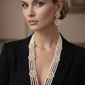May include: A woman wearing a black blazer and a multi-strand pearl necklace with gold and diamond accents. Matching gold and diamond earrings complete the look. The jewelry is the focal point.