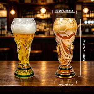 Puede incluir: Dos vasos de cerveza decorativos, de 19,5 cm de altura, con forma de trofeo. Un vaso est&aacute; lleno de cerveza. Los vasos son dorados y transparentes con una base verde. Los vasos tienen 8,5 cm de ancho.