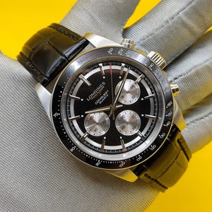 May include: A Longines Conquest Quartz chronograph watch with a black dial, silver-tone sub-dials, and a black leather strap. The watch features a tachymeter scale on the black bezel, silver hour markers, and a stainless steel case with side pushers.