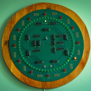 May include: A round, green circuit board clock with a wooden frame. The clock features numerous black integrated circuits, red and green LEDs, and a central design. The clock is mounted on a light green wall.