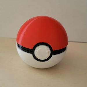 Può includere: Una Poké Ball rossa e bianca, un dispositivo sferico con una metà superiore rossa e una metà inferiore bianca, separate da una fascia nera. Un pulsante circolare bianco è centrato sulla parte anteriore. Oggetto popolare del franchise Pokémon.