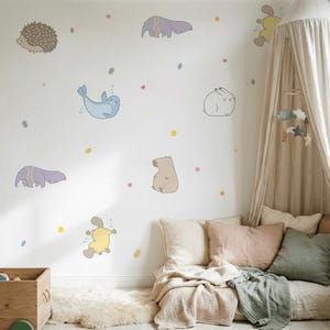 Könnte beinhalten: Eine weiße Wand, verziert mit skurrilen Tierillustrationen, darunter ein Igel, ein Elefant, eine Robbe, ein Kaninchen, ein Bär und ein Schnabeltier. Der Raum ist mit Pastellfarben und Stern- und Herzakzenten dekoriert. Ein Himmelbett und Kissen befinden sich in der Ecke.