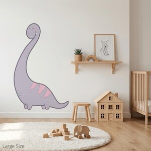 Könnte beinhalten: Ein großer, hellvioletter Dinosaurier-Wandtattoo mit rosa Akzenten. Der Dinosaurier hat einen langen Hals und ein lächelndes Gesicht. Das Tattoo befindet sich in einem Kinderzimmer mit einem Holzhaus, einem kleinen Holzschemel und einem Holz-Elefanten-Spielzeug.