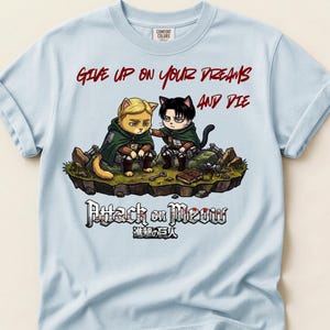 Puede incluir: Sudadera azul claro con el texto rojo "GIVE UP ON YOUR DREAMS AND DIE". El diseño presenta dos personajes de gato de "Ataque a los Titanes" con el texto "Attack on Meow" debajo.
