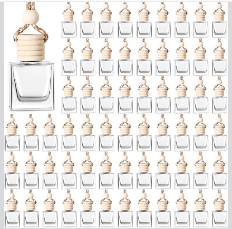 May include: A collection of clear, square glass bottles with wooden caps and hanging cords. The caps have a light wood finish and a woven rope detail. The bottles are arranged in a grid pattern, suitable for essential oils or perfumes.