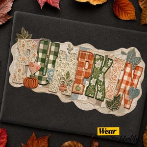 May include: A decorative sign featuring the word PUMPKIN spelled out in large, patterned letters. Each letter displays unique designs including orange and green plaid, floral prints, and botanical motifs, accented by small embroidered pumpkin and leaf icons.