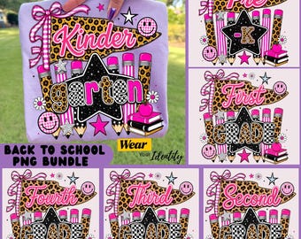 May include: A light purple t-shirt featuring a school-themed graphic with a leopard print pennant, a black star, pink and leopard print pencils, a stack of books, and smiley faces. The text reads Kinder, garten, Pre-K, First, Second, Third, and Fourth Grade.