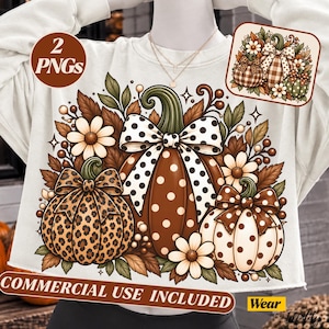 May include: A cream-colored sweatshirt featuring a graphic of three pumpkins decorated with bows, surrounded by autumn leaves and daisies. The central pumpkin has white polka dots, the left has a leopard print, and the right has brown polka dots.