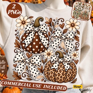 May include: A cream-colored sweatshirt featuring a graphic print of two pumpkins decorated with large white polka-dot bows. One pumpkin is brown with white polka dots, and the other has a leopard print. The design includes daisies, leaves, and hearts.