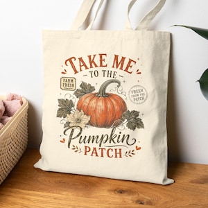 May include: A cream-colored canvas tote bag featuring a central graphic of an orange pumpkin surrounded by green leaves and flowers. The text reads "TAKE ME TO THE PUMPKIN PATCH" in brown and orange, with "FARM FRESH" and "FRESH FROM THE PATCH" labels.