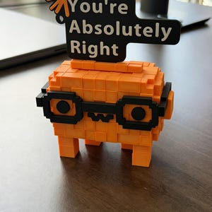 May include: An orange pixelated figure wearing black glasses, with the text "You're Absolutely Right" on a black sign above it. The figure has a star-like design on the top left of the sign.