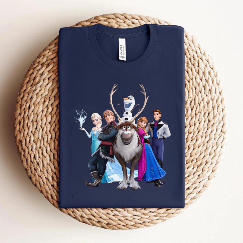 Op de afbeelding: Marineblauw T-shirt met een afbeelding van personages uit de animatiefilm Frozen. Het ontwerp omvat Elsa, Anna, Kristoff, Sven, Olaf en Hans. Het shirt is gemaakt van een zacht materiaal en wordt gepresenteerd op een geweven oppervlak.