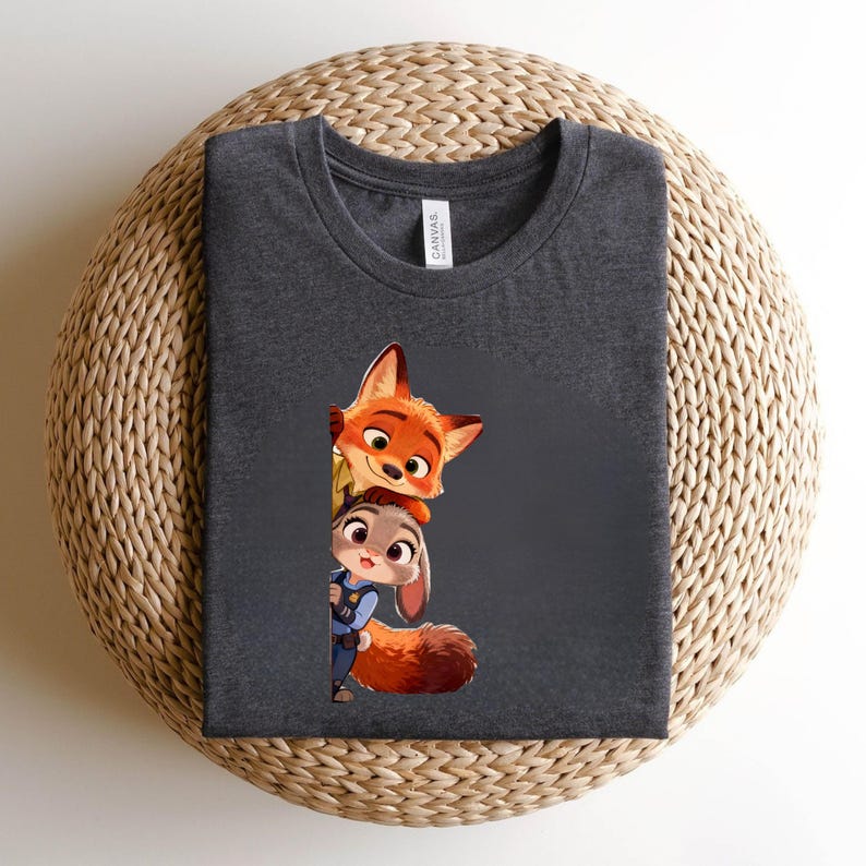 May include: A dark charcoal gray crew neck t-shirt featuring a graphic print of a cartoon fox and a cartoon rabbit peeking out from behind a vertical edge. The fox is orange with large eyes, and the rabbit is gray with large eyes and a blue uniform.
