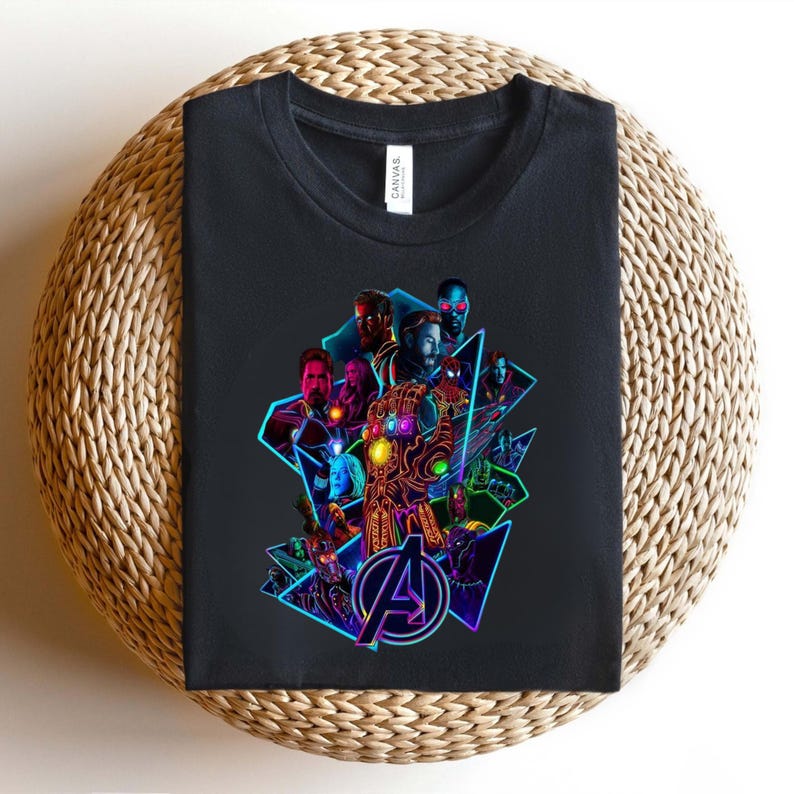 May include: Black t-shirt with a vibrant graphic of superheroes, including Iron Man and Captain America, and the Avengers logo. The design features a glowing gauntlet and geometric shapes.