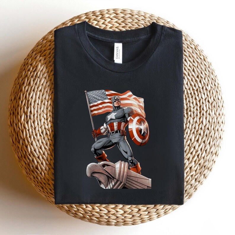 Pode incluir: Camiseta preta com um gr&aacute;fico do Capit&atilde;o Am&eacute;rica segurando uma bandeira americana e um escudo. A ilustra&ccedil;&atilde;o mostra o Capit&atilde;o Am&eacute;rica em uma &aacute;guia de pedra. A camisa tem gola redonda e &eacute; feita de um material macio.