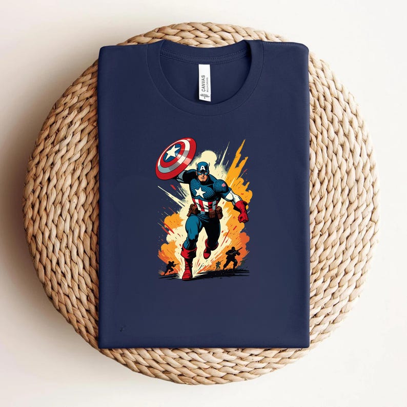 May include: Navy blue t-shirt featuring a graphic of Captain America with his shield, set against an orange and yellow explosion background. The illustration is in a comic book style.